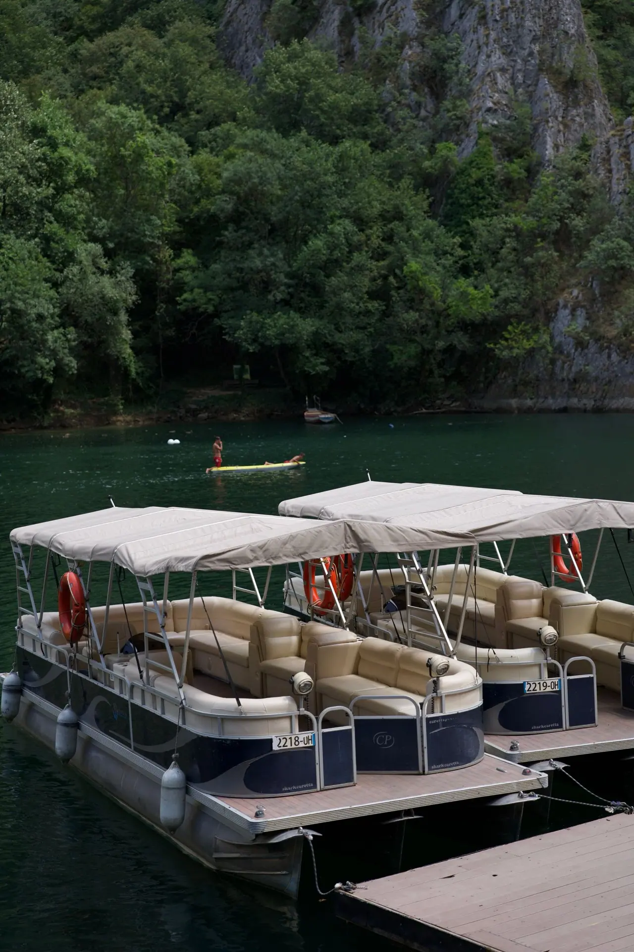 Two pontoon boats tied to a dock on a forest lake