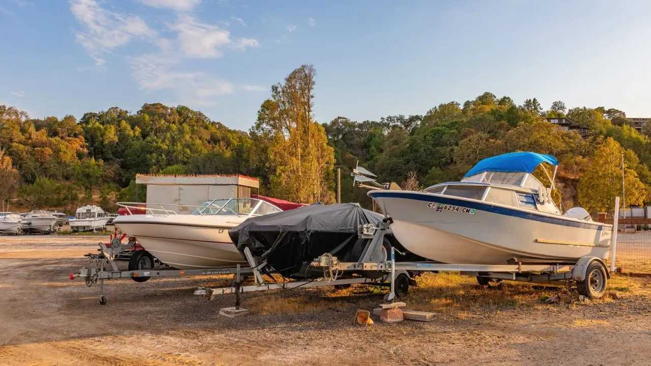 Motorboats on trailers parked in rows on a grass storage lot