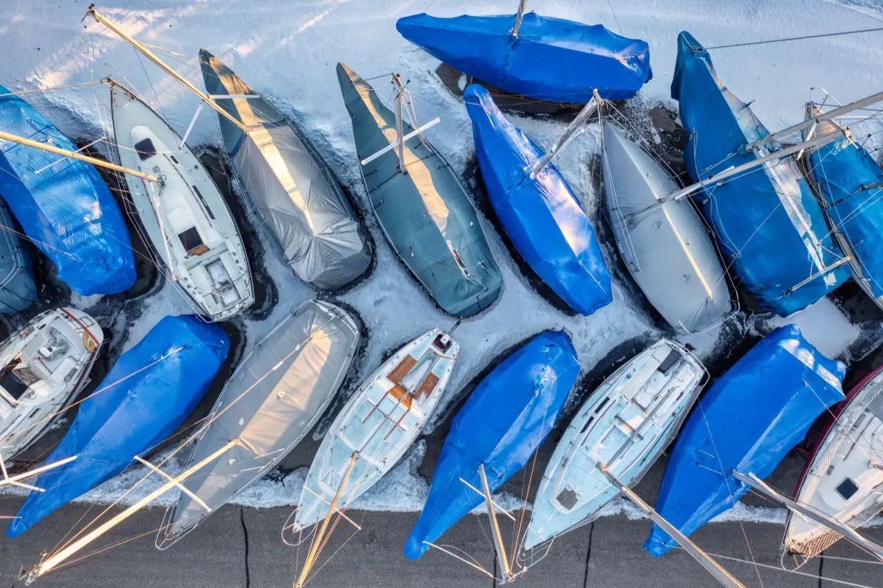 Rows of sailboats under winter covers in a boatyard seen from above